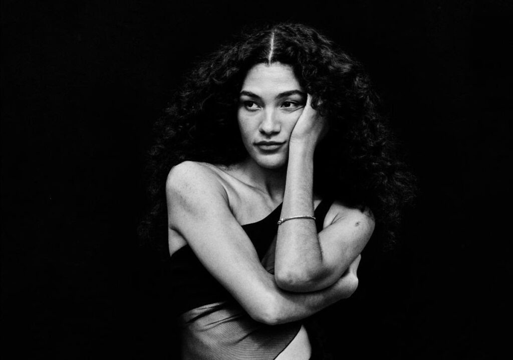 Fotografía promocional de la artista británica Olivia Dean, en blanco y negro.