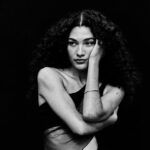 Fotografía promocional de la artista británica Olivia Dean, en blanco y negro.
