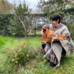 Mauricia Saavedra, protagonista de "Yo no canto por cantar", tocando la guitarra en el jardín de una casa.