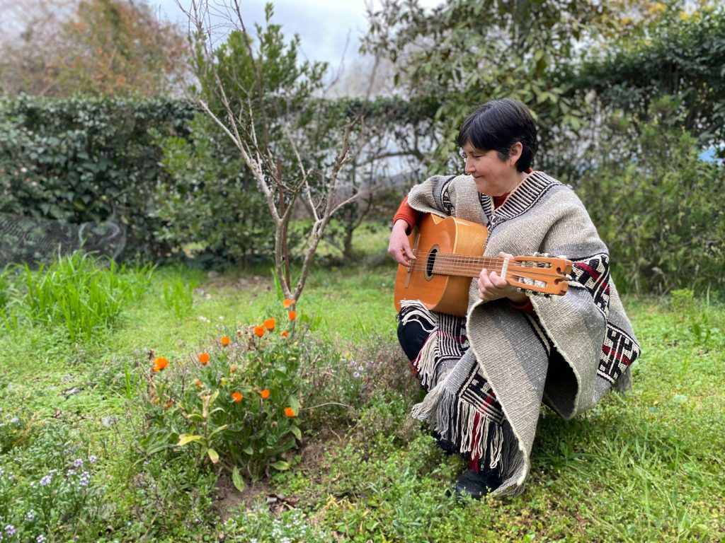 Mauricia Saavedra, protagonista de "Yo no canto por cantar", tocando la guitarra en el jardín de una casa.
