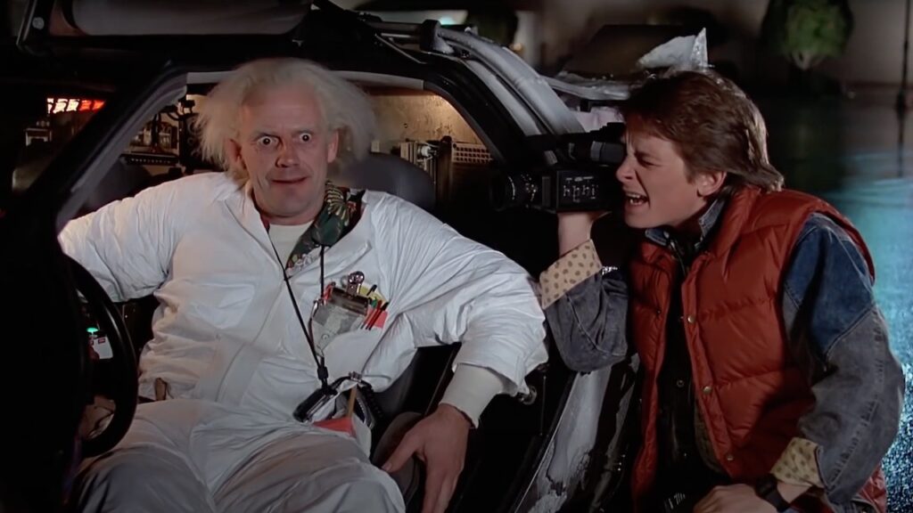 Emmett "Doc" Brown y Marty McFly, protagonistas de la película "Volver al futuro", junto a la máquina del tiempo DeLorean.